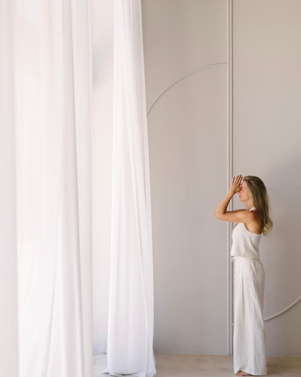 Elle standing small against a sunlit curtain