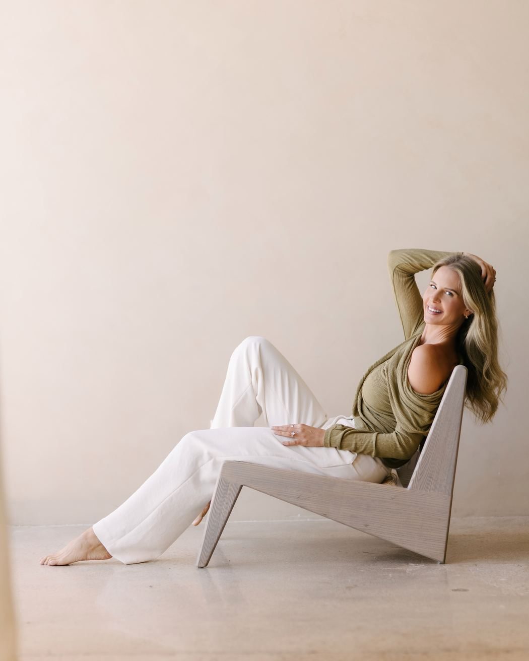 Elle reclining in a sculptural chair, relaxed and smiling