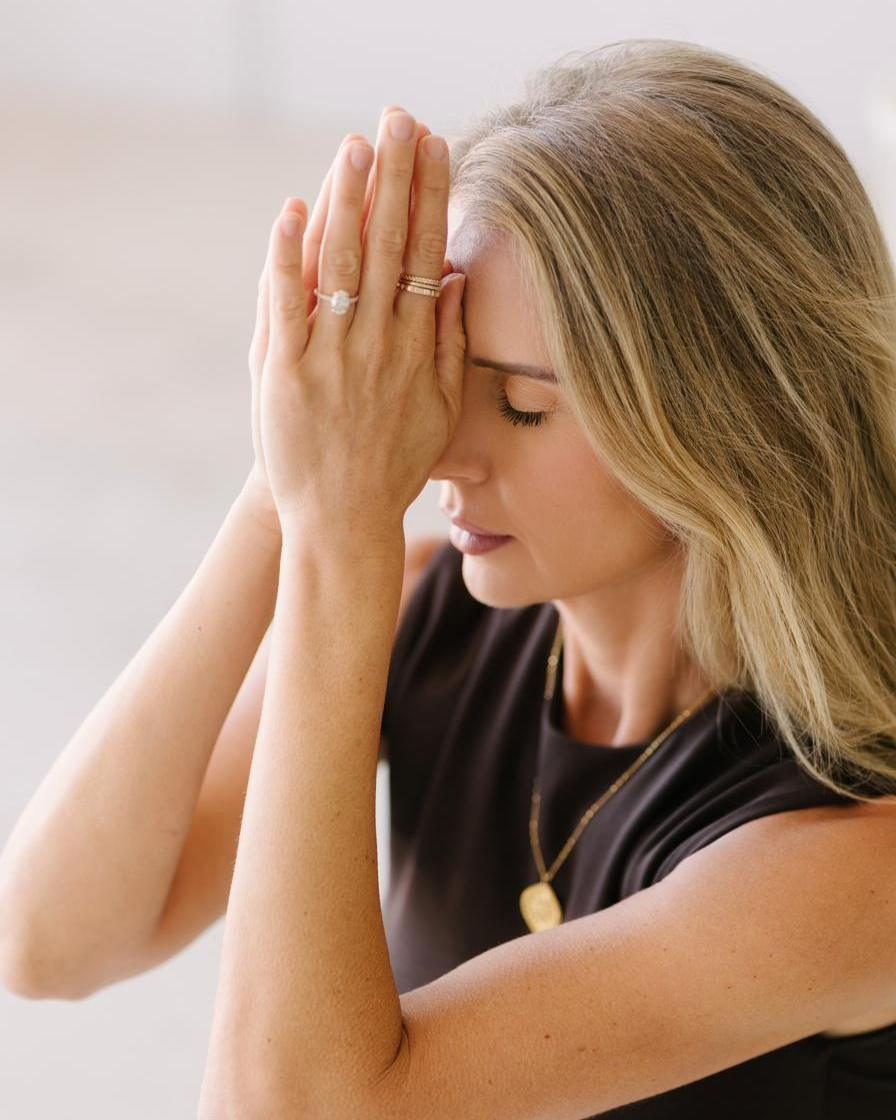 Elle with both hands pressed to her forehead, eyes closed