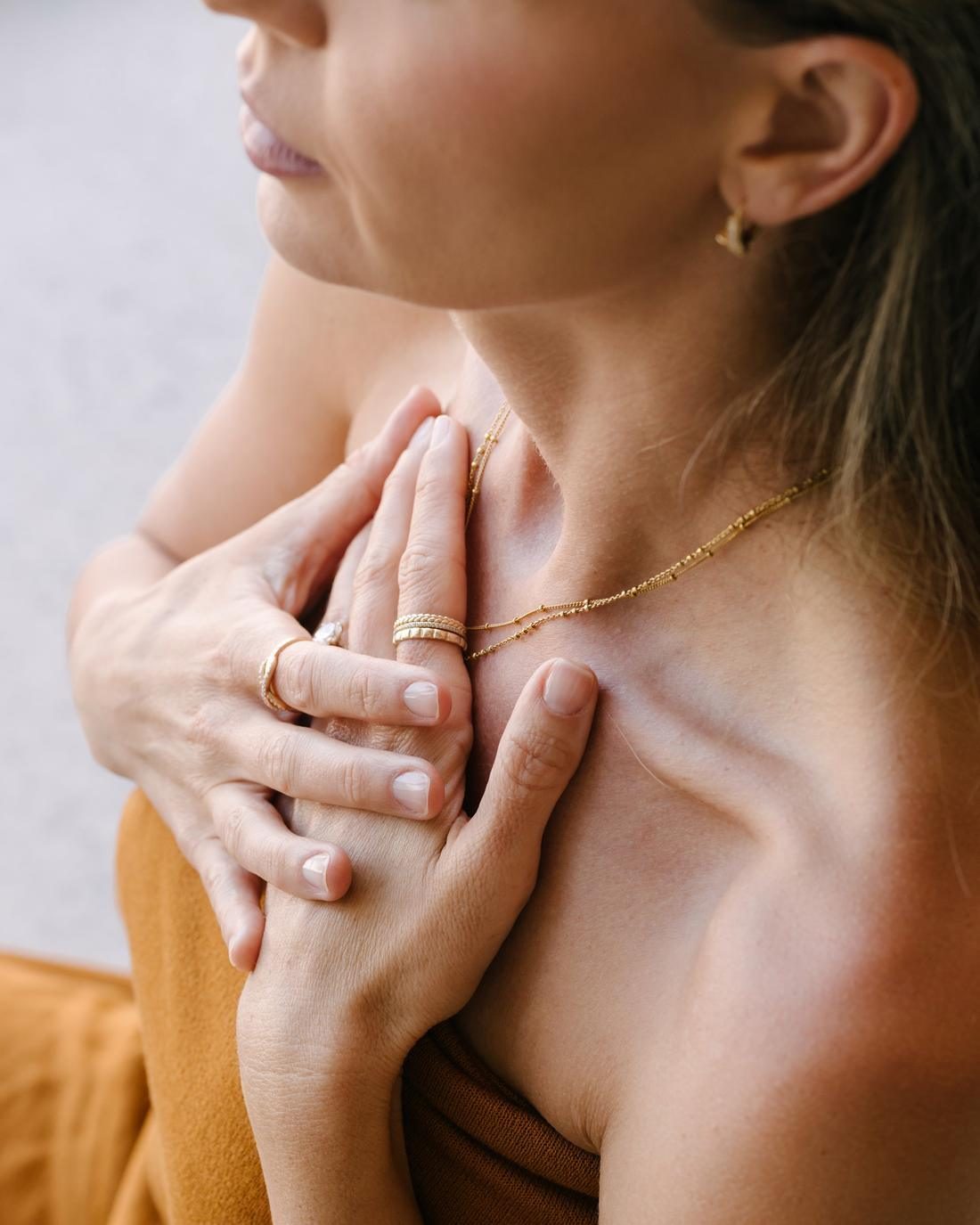Close detail of Elle’s hands resting at her collarbone, eyes closed