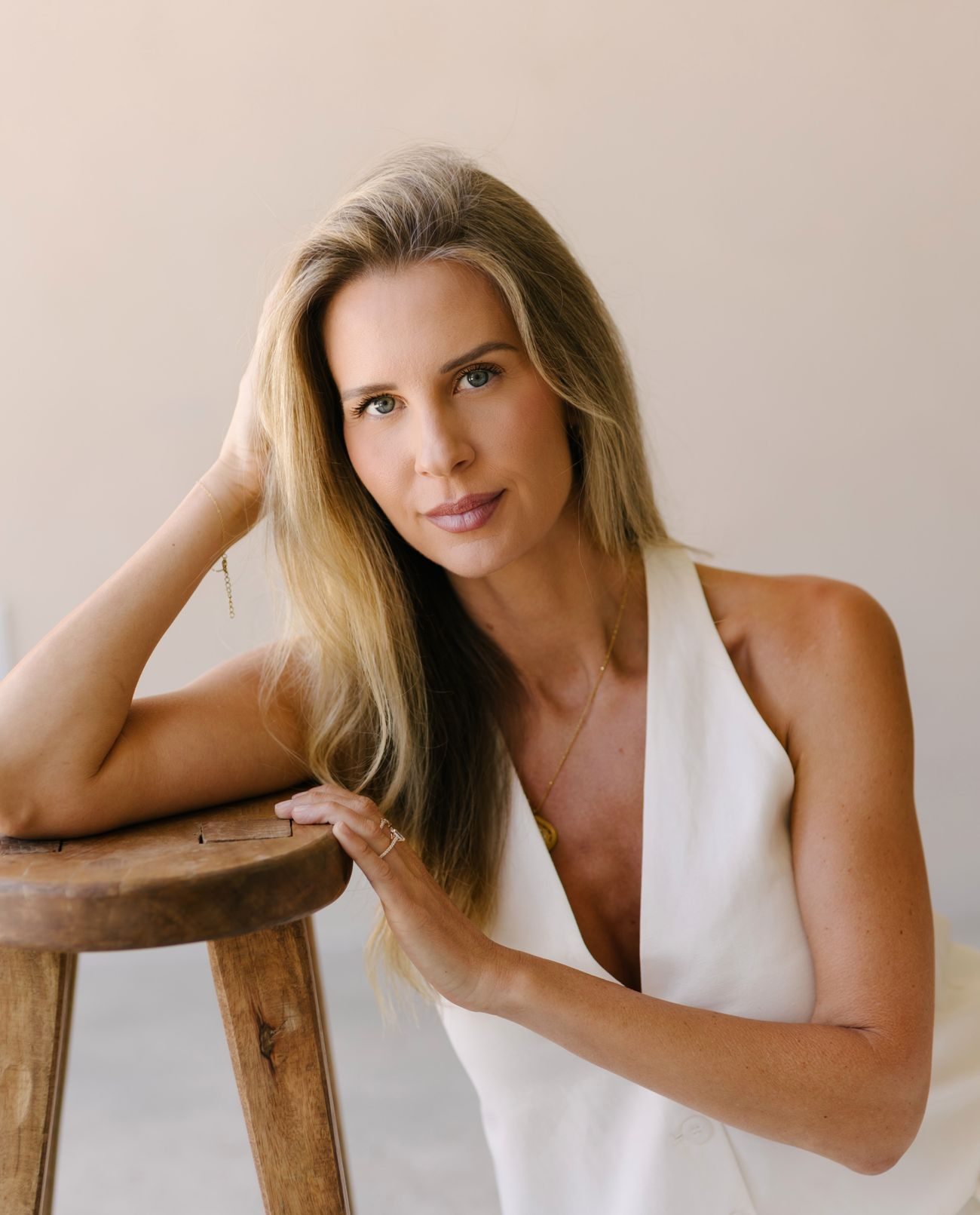 Elle Wilk leaning on a wooden stool, looking toward the camera