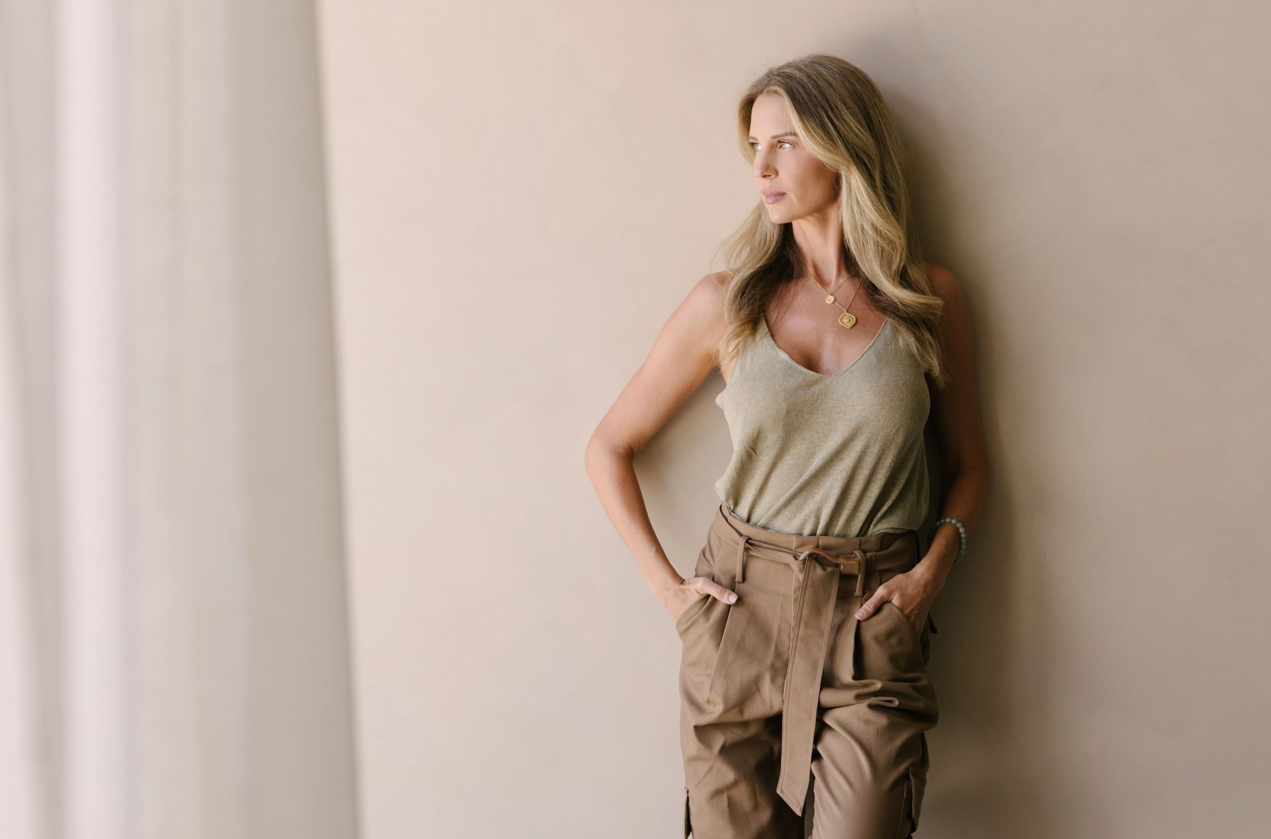 Elle Wilk standing against a sunlit plaster wall