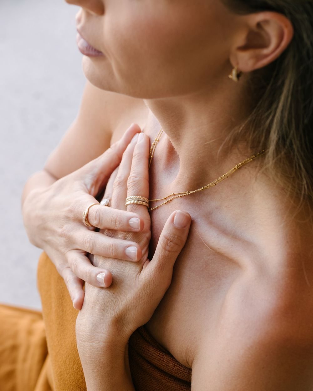 Close detail of Elle’s hands resting at her collarbone
